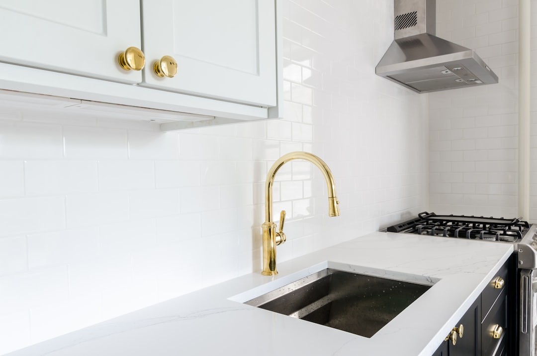 White & Black kitchen with gold faucets and gold finishings. Black & white checkered floor. Marble countertop. Black kitchen cabinets. White kitchen cabinets. 